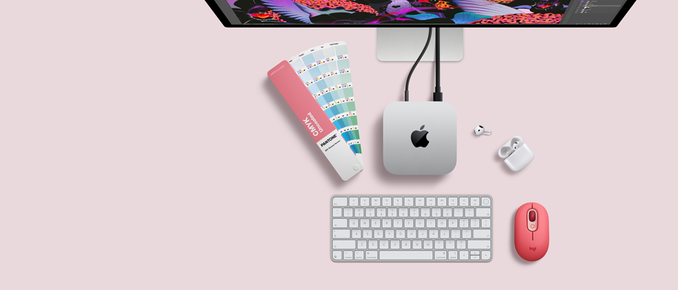Mac mini, Oberseite, Aluminium Silber, gerundete Ecken, glänzendes schwarzes Apple Logo in der Mitte, verbunden über ein Kabel, Studio Display oben teilweise sichtbar, AirPods 4, geöffnet, Pantone Farbpaletten, Logitech Tastatur und Maus in Rot